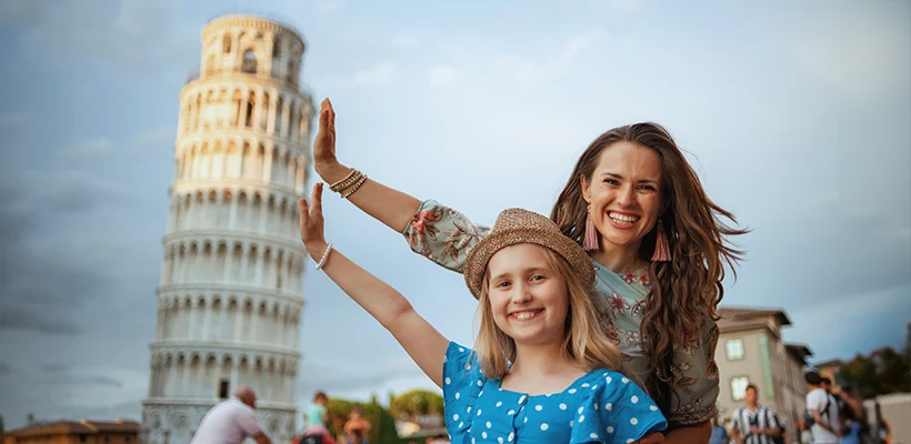 Joyeuse et élégante mère et fille posant à laTour de Pise, en Italie.